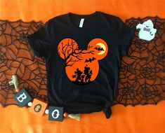 a mickey mouse halloween shirt sitting on top of a bed next to a spooky ghost