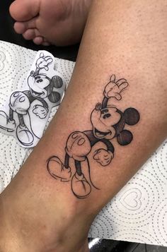 a person with a mickey mouse tattoo on their arm and leg, sitting next to each other