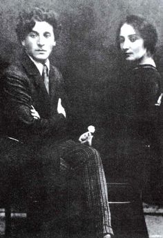 an old black and white photo of two people sitting next to each other on a chair