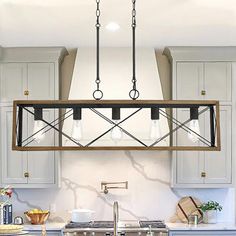 a kitchen with white cabinets and an island in front of the stove top is lit by three hanging lights