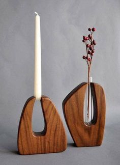 two wooden vases with a white candle in one and red berries in the other