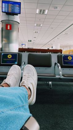 a person's feet resting on an airport bench