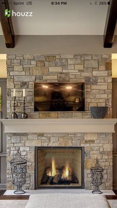 a living room with a fire place in the center and a tv above it on top of a stone fireplace