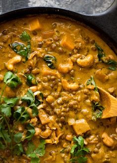 a skillet filled with chicken and spinach in a curry sauce, garnished with cilantro