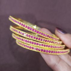 "* Handcrafted Gold Plated 2 Bangle Set. Sold as a set. * Bangles with pretty Semi precious Ruby and emerald stones * High Quality 22 K Gold Plated- 2 Bangle set Bangles Sizes : 2.6 ( 2.34\" diameter of the inner circle); The Gorgeous gold-plated bangle/ bracelet best exemplifies the careful craftsmanship done on it -- a specialty at Nemali Jewelry. It has a special tone of elegance attached to it. The intricate handmade design of the bangle/bracelet set gives it a fresh and original look. Look Pink Ruby Round Bracelets, Celebration Bangle Bracelet With Stone Setting, Festive Ruby Jeweled Bracelets, Festive Jeweled Ruby Bracelets, Celebration Stone Setting Bangle Bracelet, Jeweled Round Bangle As Gift, Jeweled Round Bracelets For Celebration, Pink Hand-set Bangle Jewelry, Stackable Pink Bangle For Parties