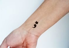 a small black cat tattoo on the wrist