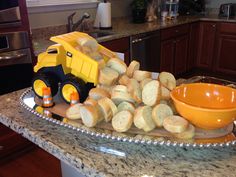 a yellow toy truck sitting on top of a kitchen counter next to bread slices and a bowl