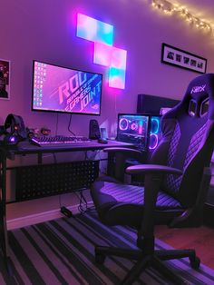 a gaming room with two computer monitors on the wall and a chair next to it