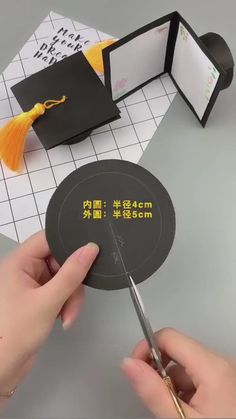 a person cutting out a piece of paper with scissors and some other items on the table