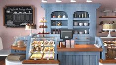 the interior of a bakery with cakes and pastries on display in blue cupboards