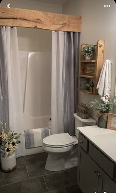 a white toilet sitting in a bathroom next to a bath tub and shower head mounted on a wooden frame