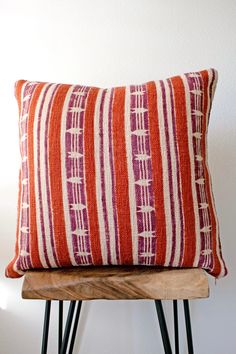 a red and white striped pillow sitting on top of a wooden chair