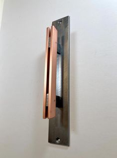 a metal object mounted to the side of a white wall with wood trim on it