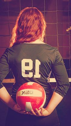 a woman holding a volleyball in her hands