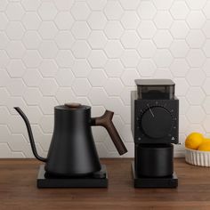 a black coffee pot sitting on top of a wooden table