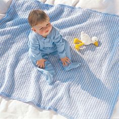 a baby sitting on a blanket next to two rubber ducks