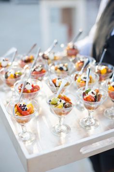 a tray filled with lots of desserts on top of a white tablecloth covered floor