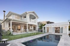 a large house with a pool in front of it and an outdoor dining area on the other side