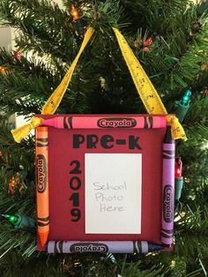 a school photo frame ornament hanging from a christmas tree with crayons on it