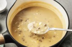 a pot filled with soup sitting on top of a table next to a wooden spoon