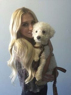 a woman holding a white dog in her arms