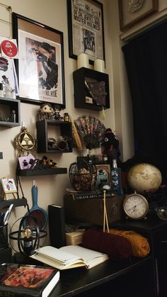 there is a desk with many items on it and pictures hanging above the top shelf