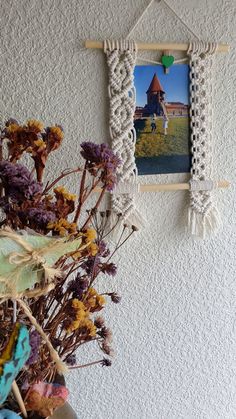 two pictures hanging on the wall with flowers in front of them and a plant next to it