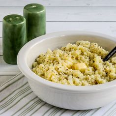 a white bowl filled with food on top of a table next to two green candles