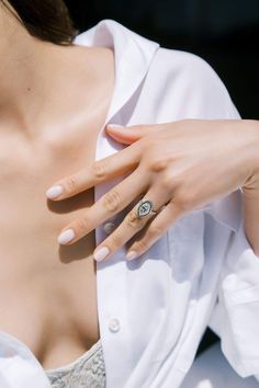 a woman wearing a white shirt with a ring on her left hand and an open bra