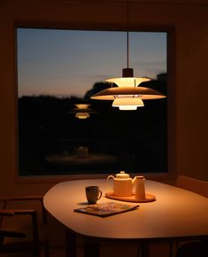 a table with a teapot and cup on it in front of a window