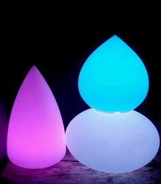 three different colored lights sitting next to each other on top of a wooden table in the dark