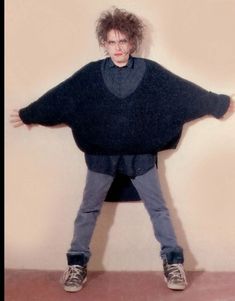 a man is standing with his arms spread out in front of him, wearing an oversized sweater