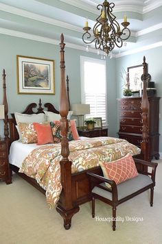 a bedroom with a four post bed and chandelier