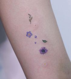 a close up of a person's arm with flowers and leaves on the side