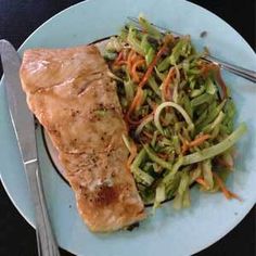 a white plate topped with meat and veggies next to a knife and fork