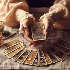 a woman holding a deck of playing cards in her hands, surrounded by candles and other decorative items