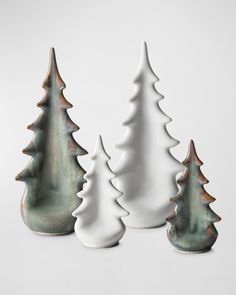 three white ceramic christmas trees are shown in this image, one is green and the other is white