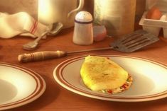 an omelet sitting on top of two white plates next to utensils