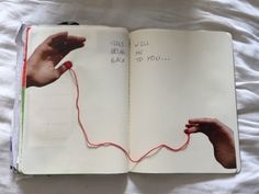 an open book with writing on it and two hands reaching for the red string that goes through them