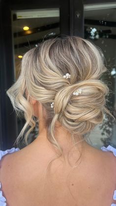 a woman with blonde hair wearing a white dress and pearls in her hair, looking out the window