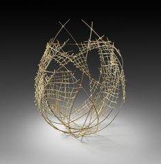 an artistic sculpture made out of wire on a white surface with light from the top