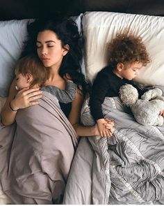 a woman laying in bed next to a child