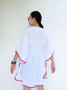 "🚚..ALL ORDERS ARE SHIPPED VIA DHL EXPRESS MAIL Opt for the perfect beach cover up with this white kaftan cut with kaftan sleeves, v-neck with drawstring tie closure and pom pom trim along edges. Layer it over your brightly color bikinis for a beach ready look. It's an irresistibly stylish choice for sun-soaked getaways. * Pull-on style * V-neck with drawstring tie closure * Kaftan sleeve. * Red, white and blue pom pom trim along edges * Ruched waistline detail at center front and center back * Long Tasseled Kimono For Beach Cover-up, Long Tasseled Kimono For Vacation, Red V-neck Kaftan For The Beach, Summer Beachwear Kaftan With Back Tassel Tie-up, Red Kimono For Beach Cover-up, Free Size V-neck Kimono For Vacation, Vacation V-neck Free Size Kimono, Spring Kaftan With Tassels And Kimono Sleeves, Summer Dresses With Kimono Sleeves In White