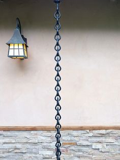 a lamp hanging from the side of a building next to a wall with a light on it