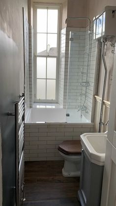 a bathroom with a toilet, sink and bathtub next to a window in the wall