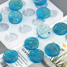 blue and gold decorated cupcakes sitting on top of an ice tray next to flowers