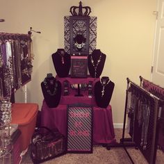 there are many necklaces on display in the room with purple table cloth and black jewelry