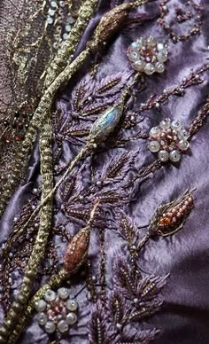 the back of a purple dress with beading on it