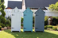 three blue and one white beach huts in the grass