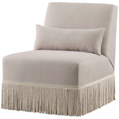 a beige chair with fringe trim and pillows